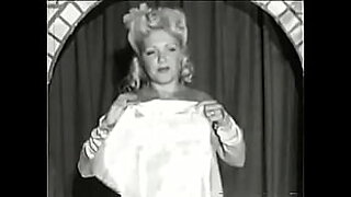 Curly blonde with huge tits takes part in an erotic performance of the 60s