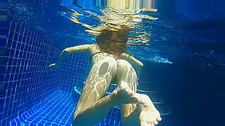 3人の官能的なエボニー女性がプールにダイブし、遊びながら水しぶきを飛ばす。