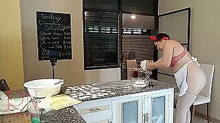 Nudist housekeeper Regina Noir cooking at the kitchen. Naked maid