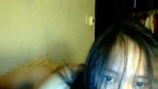 Una joven oriental revela sus pequeños senos en la webcam.
